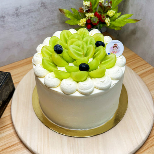 White cake with green fruit decoration on a wooden table