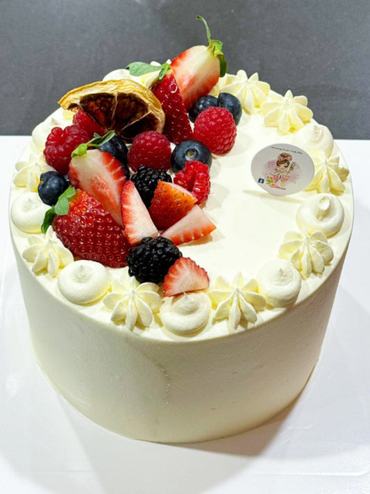 Decorative cake with whipped cream and fresh berries on a white surface.