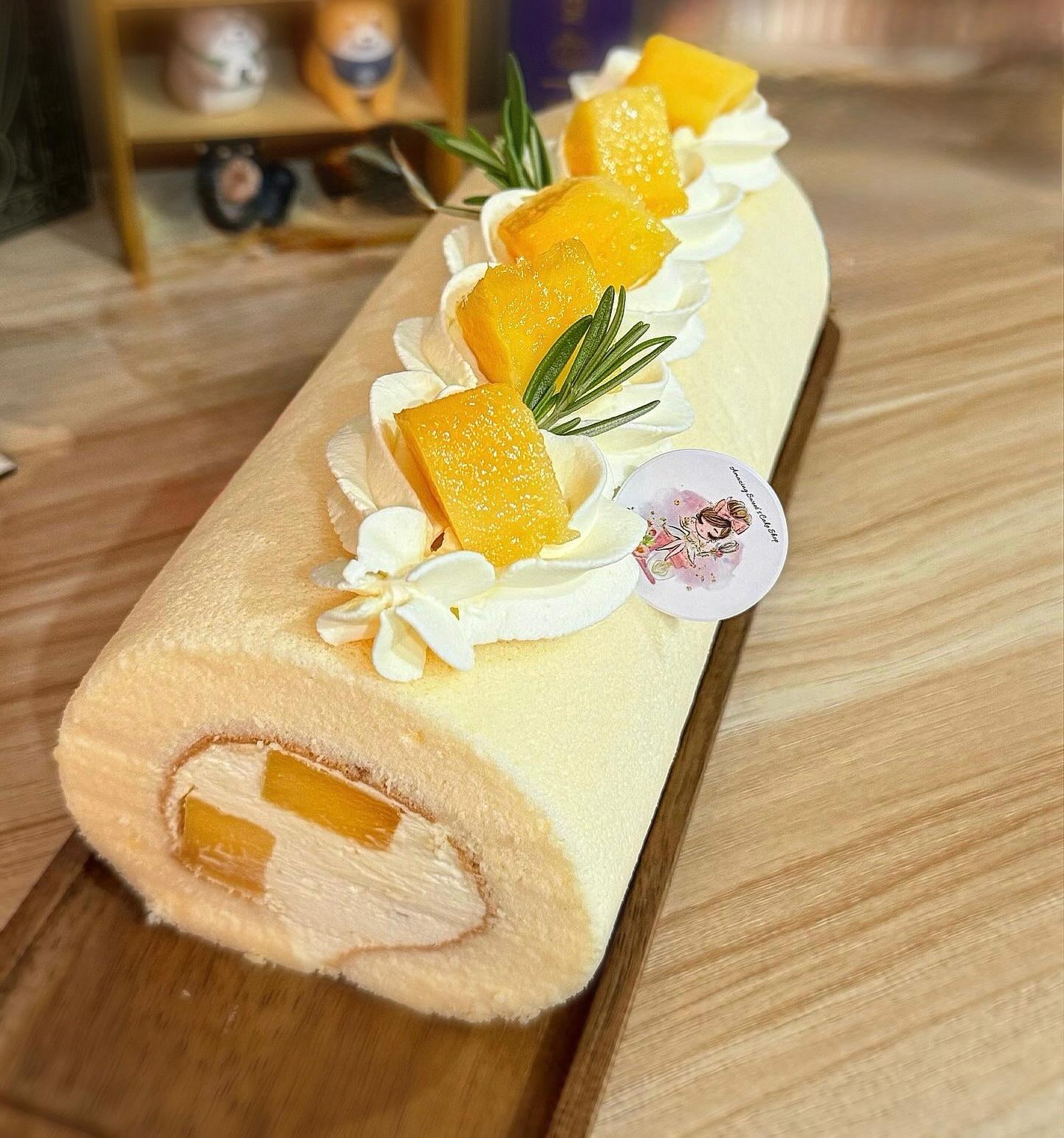 Roll cake with yellow filling and white cream on a wooden surface