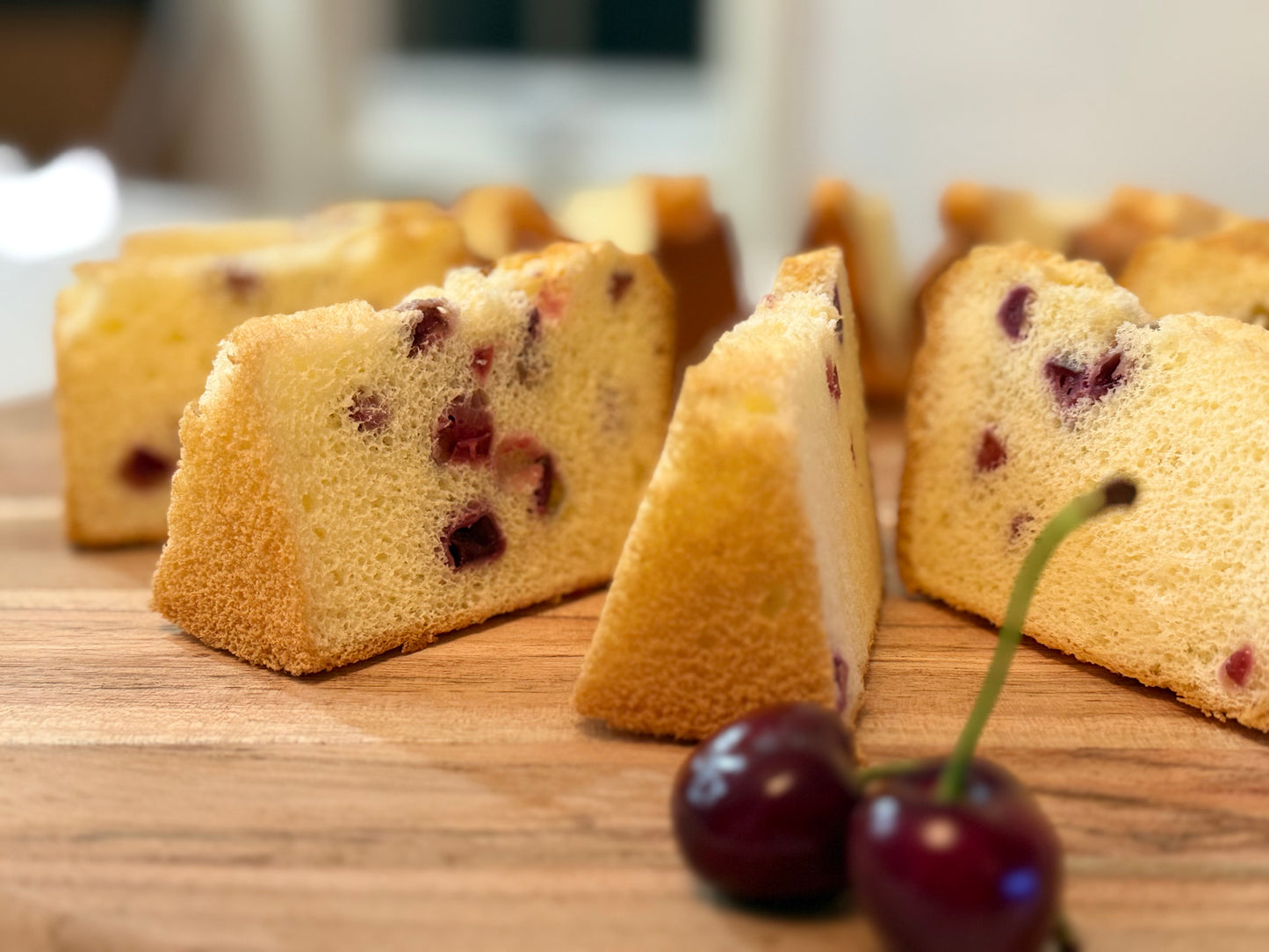 Slices of cake with cherries on a wooden surface