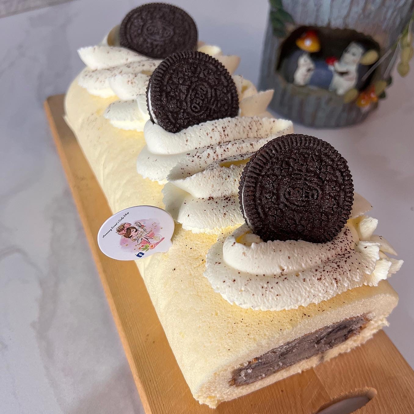 Roll cake with Oreo cookies on top, placed on a wooden board.