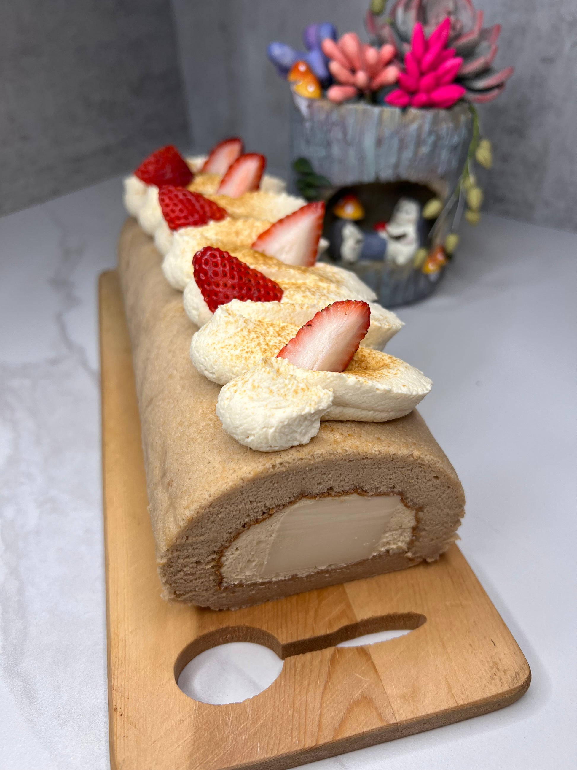 Slice of cake roll with strawberries on a wooden board