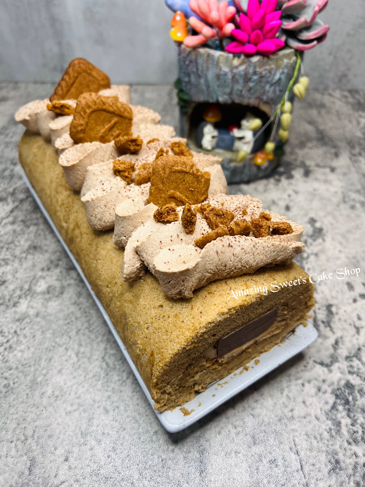 Decorative cake with animal shapes on a gray surface, featuring 'Amazing Sweets Cake Shop' branding.