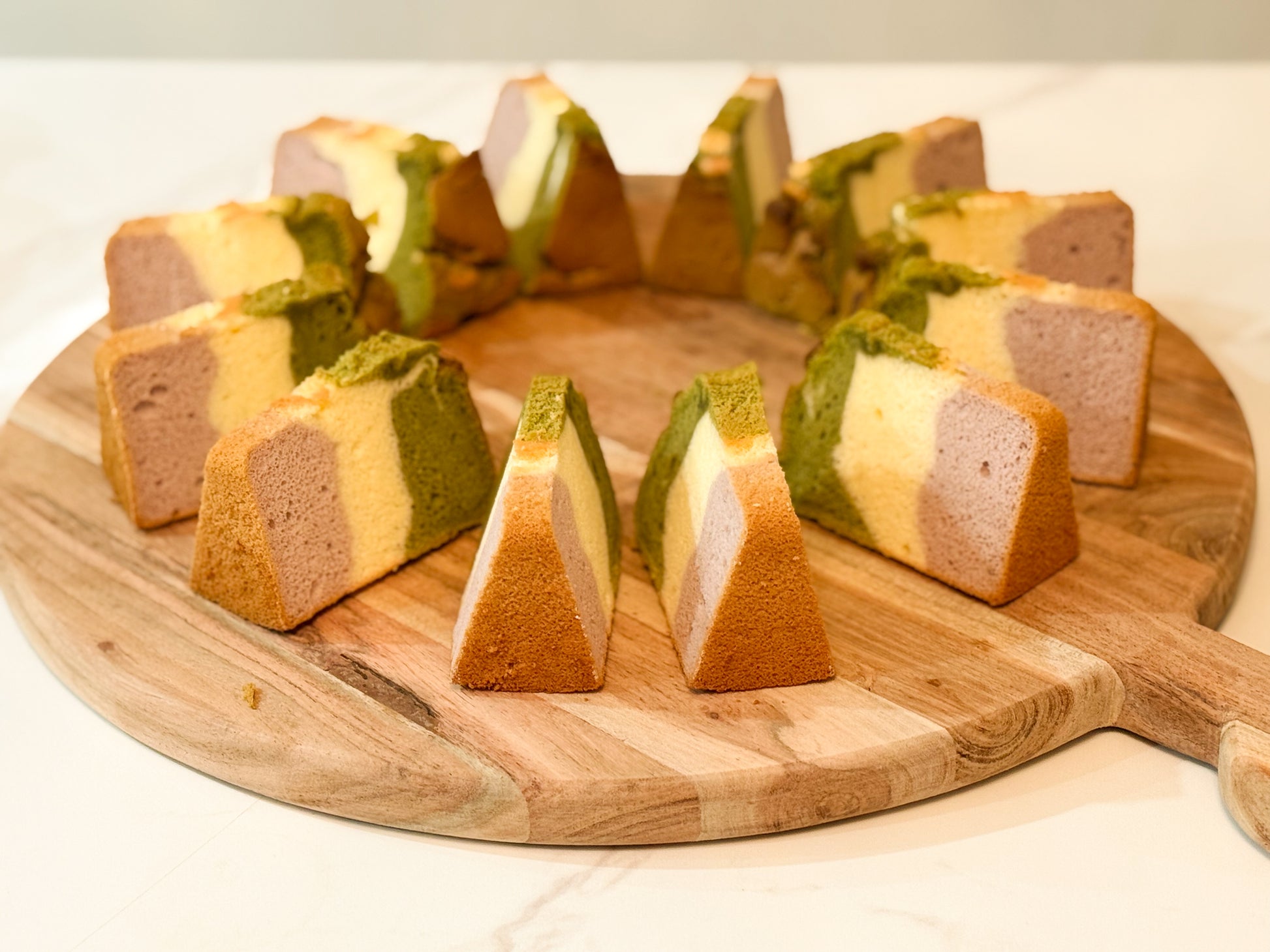Sliced layered cake on a wooden board with a white background