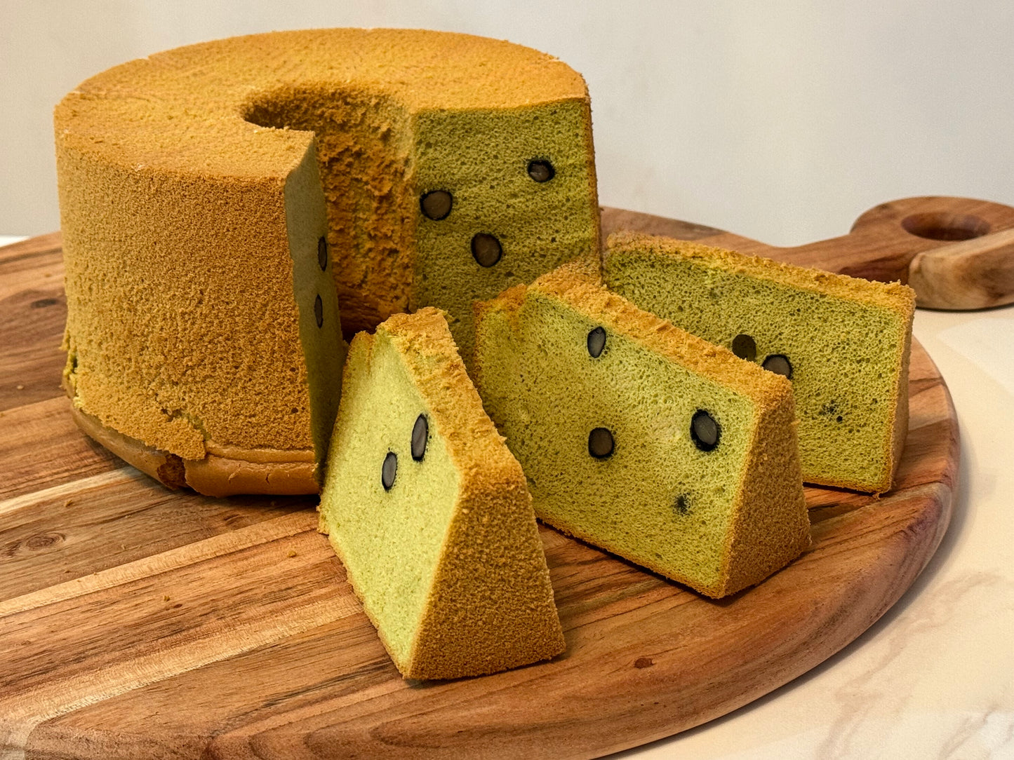 Green tea cake with slices on a wooden board