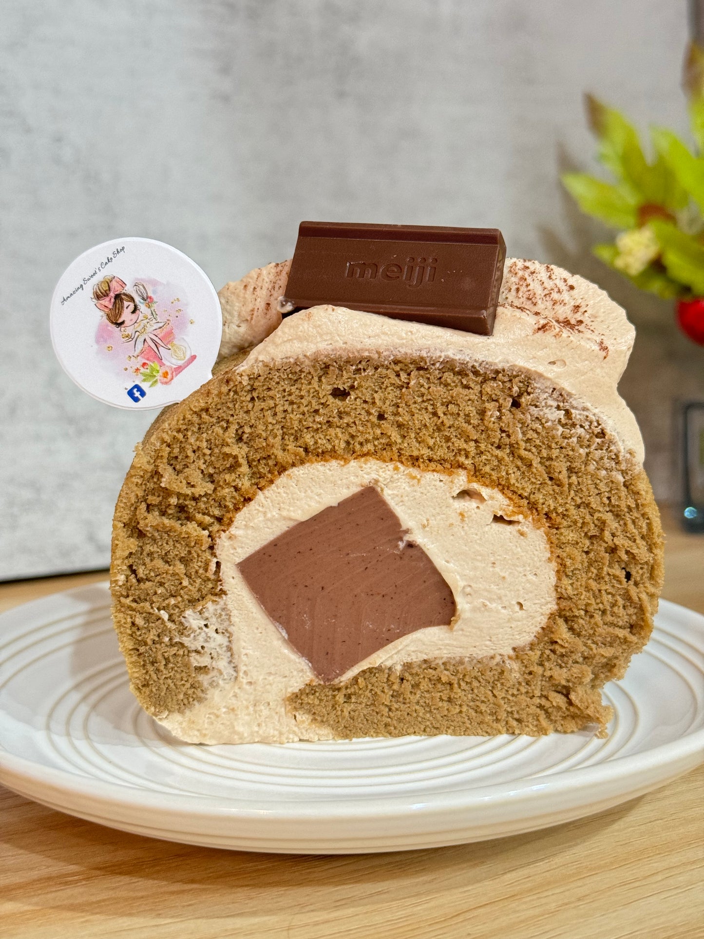 Close-up of a coffee roll cake with chocolate filling on a white plate.