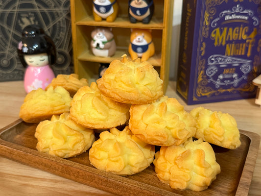 Baked pastries on a wooden tray with decorative items in the background
