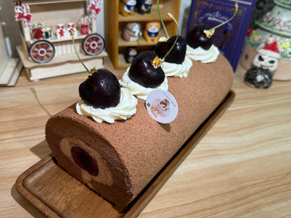 Chocolate roll cake with cherries on top on a wooden board, set against a blurred background.